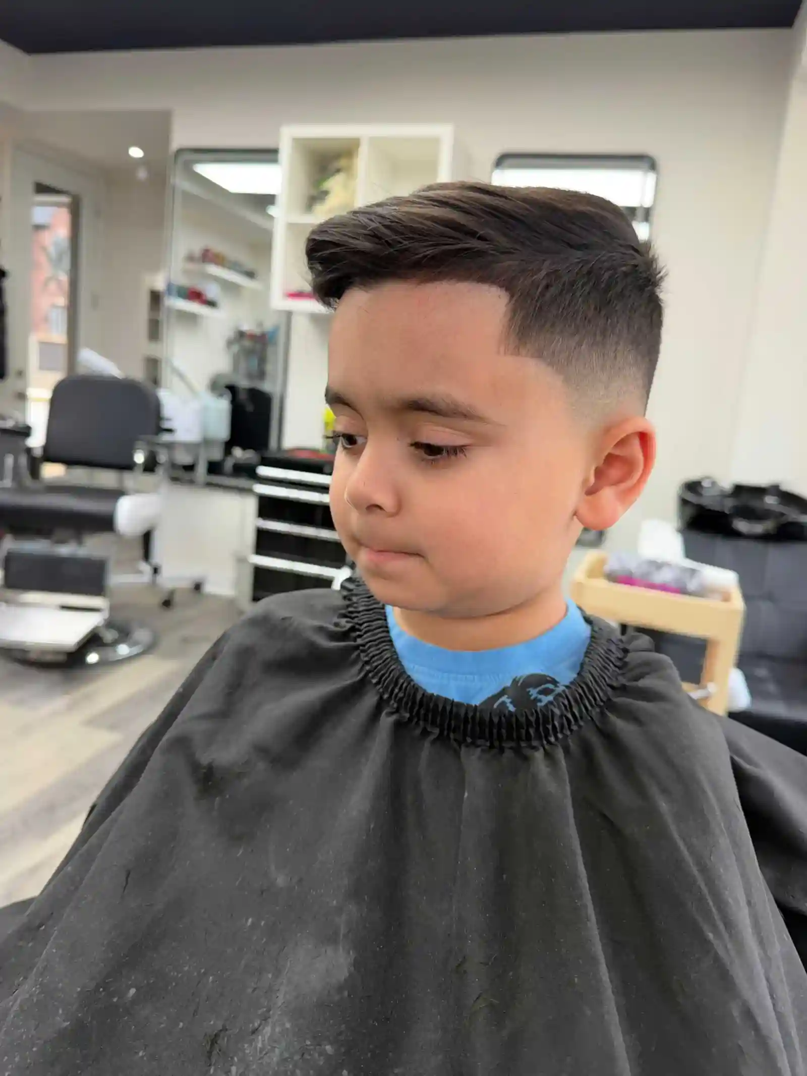 Young boy with a clean side part comb over haircut and low taper fade at an Oakville barbershop