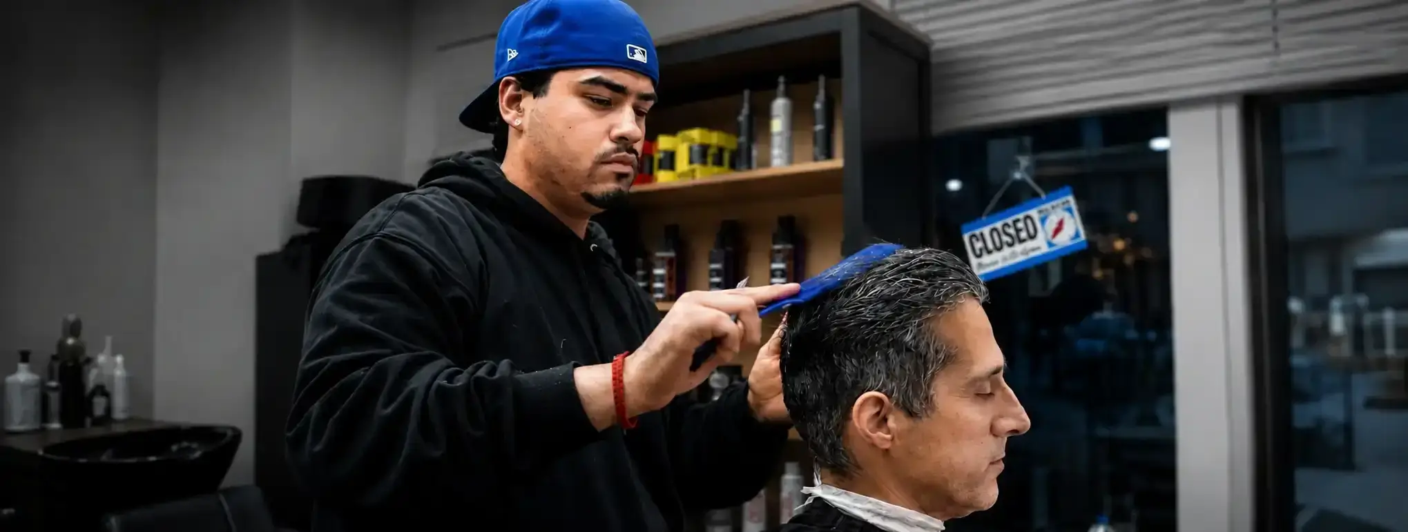 A man receiving a professional men’s haircut in Oakville while a barber carefully styles his hair with a comb inside a modern barbershop.